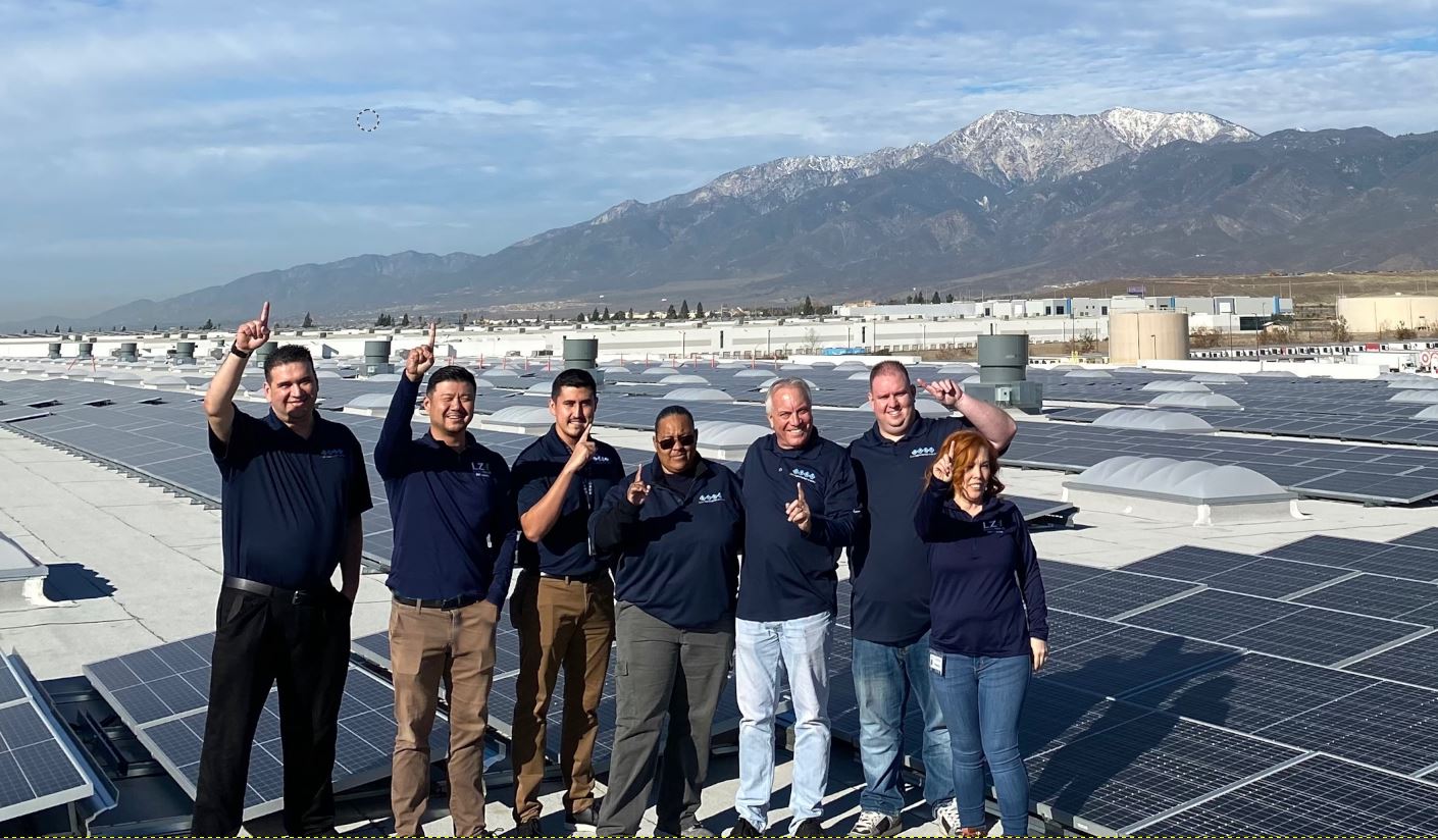 ctdi team smiling with solar panels and mountains in the background